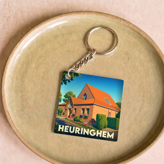 Porte-clés souvenir de la ville de Heuringhem avec une illustration stylisée d'une maison.