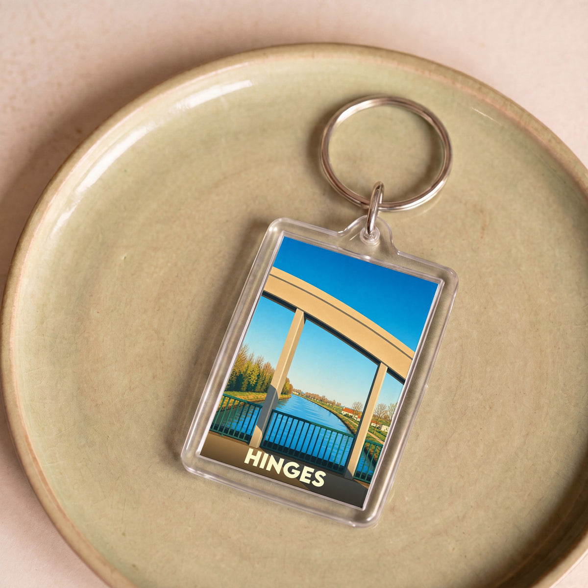 Porte-clés souvenir de la ville de Hinges avec une illustration stylisée de son pont au-dessus du canal.
