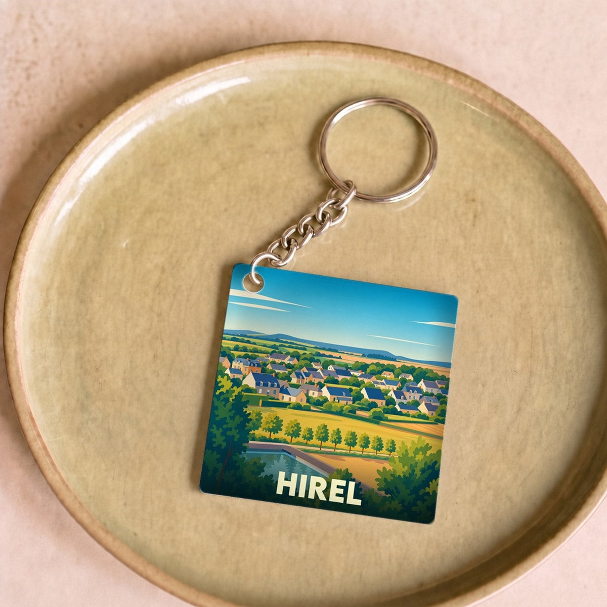 Porte-clés souvenir de la ville de Hirel avec une illustration paysagère stylisée.
