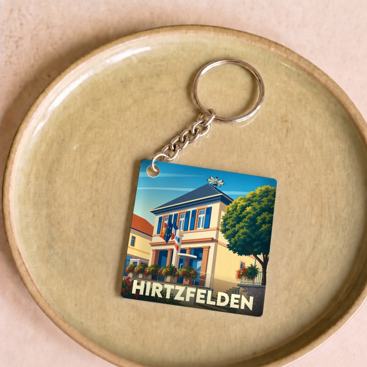 Porte-clés souvenir de la ville de Hirtzfelden avec une illustration stylisée de sa mairie.