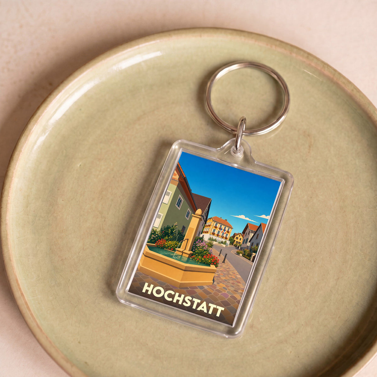 Porte-clés souvenir de la ville de Hochstatt avec une illustration stylisée d'une fontaine et de maisons colorées.