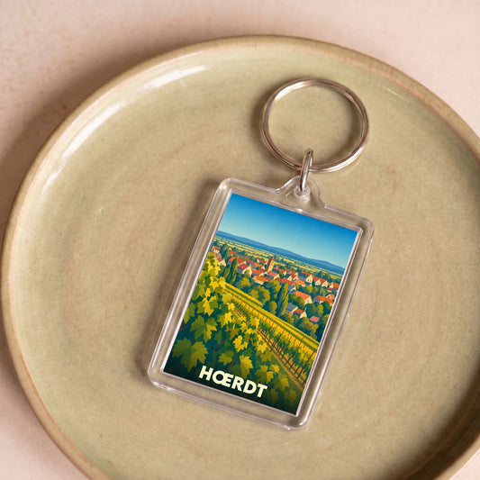 Porte-clés souvenir de la ville de Hœrdt avec une illustration stylisée de vignobles et du village.