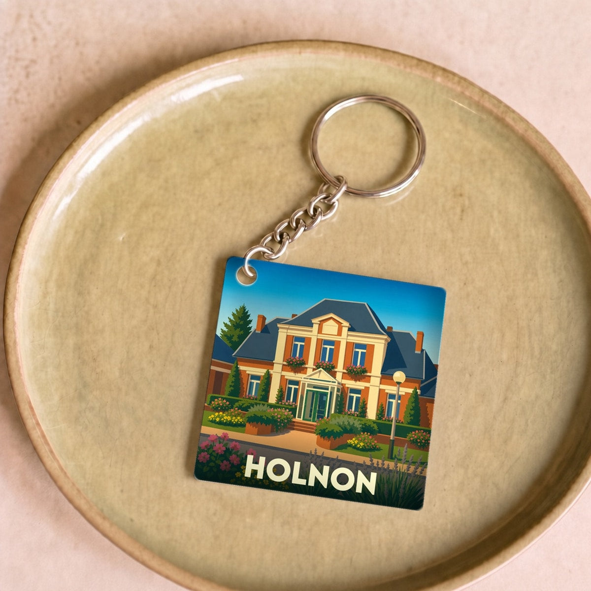 Porte-clés souvenir de la ville de Holnon avec une illustration stylisée d'une demeure bourgeoise.