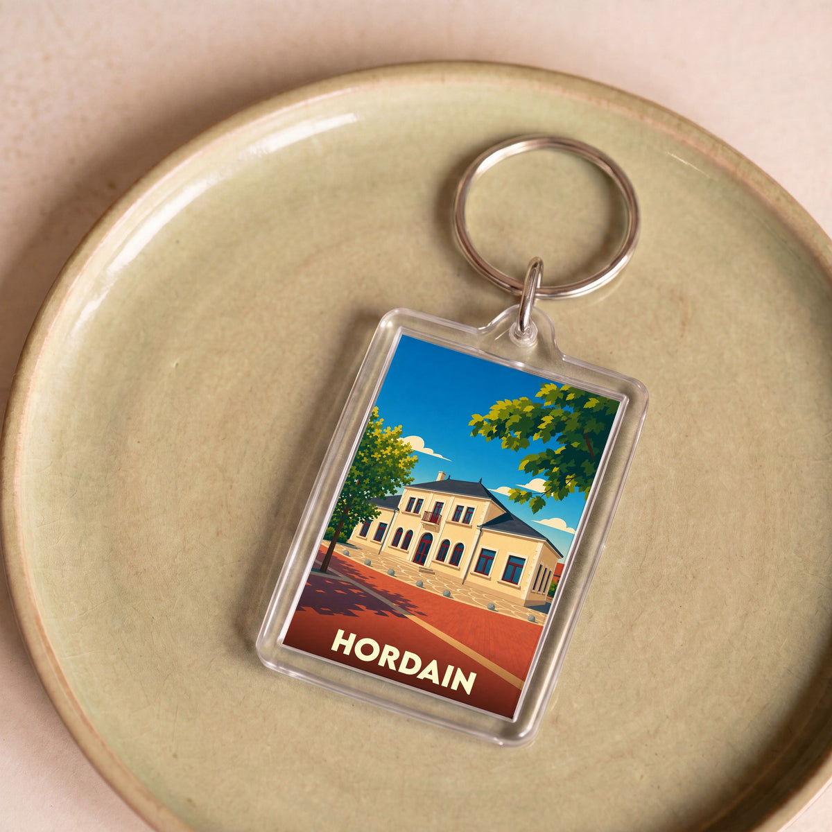 Porte-clés souvenir de la ville de Hordain avec une illustration stylisée d'un bâtiment emblématique.