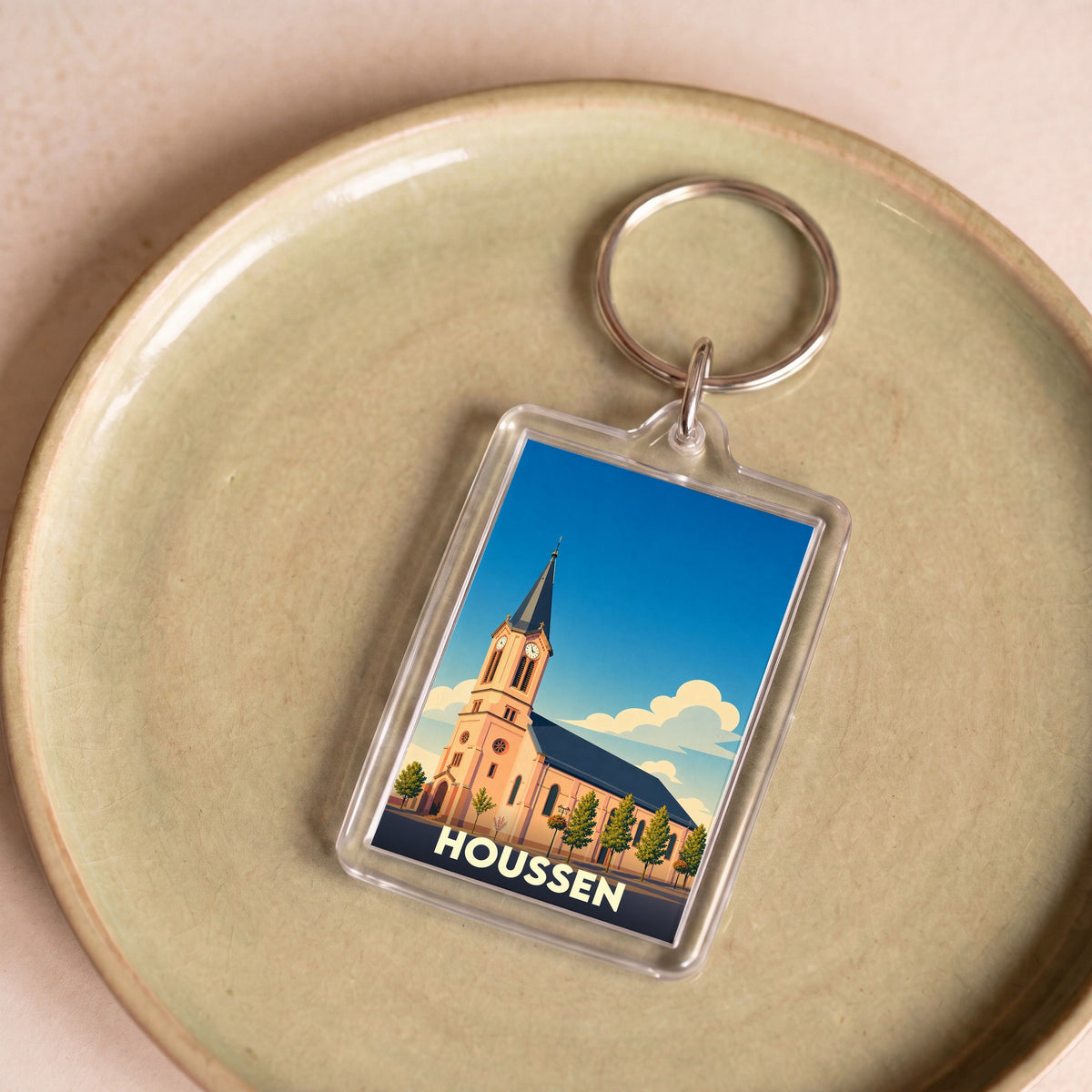Porte-clés souvenir de la ville de Houssen avec une illustration stylisée de son église.