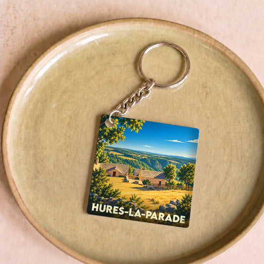 Porte-clés souvenir de la ville de Hures-la-Parade avec une illustration stylisée d'un paysage de campagne.