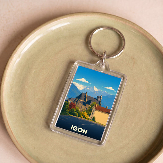 Porte-clés souvenir de la ville d'Igon avec une illustration stylisée des montagnes et de l'église locale.
