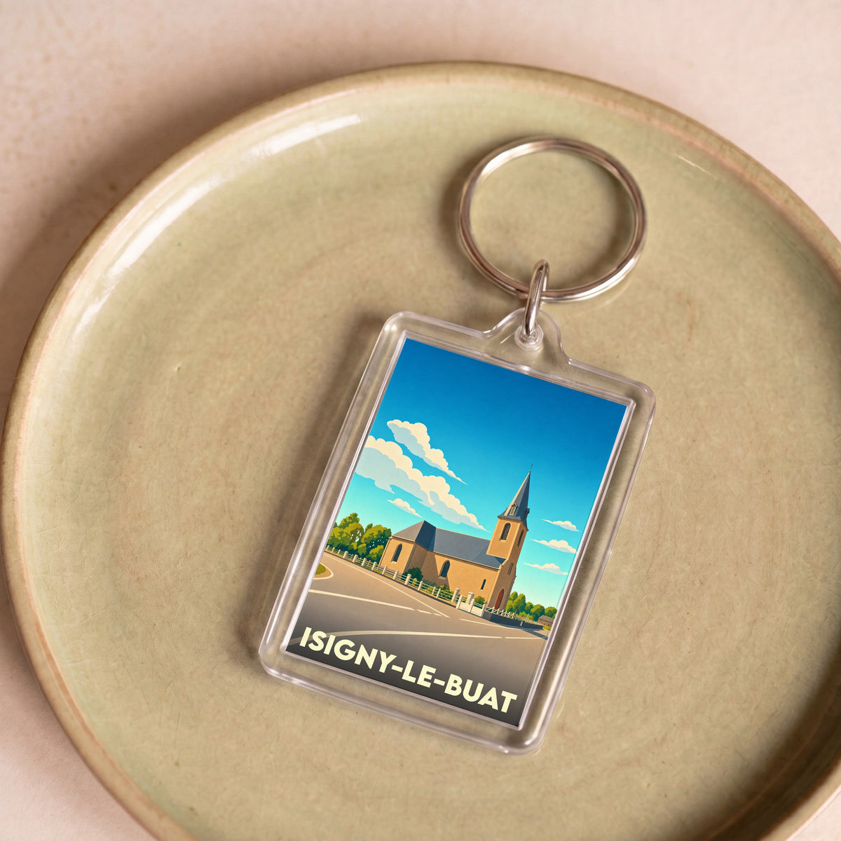 Porte-clés souvenir de la ville d'Isigny-le-Buat avec une illustration stylisée de son église.