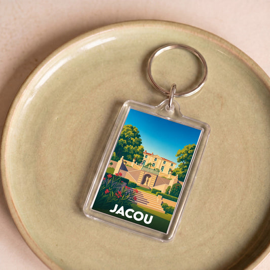 Porte-clés souvenir de la ville de Jacou avec une illustration stylisée d'un domaine historique.