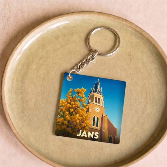 Porte-clés souvenir de la ville de Jans avec une illustration stylisée d'une église et d'un arbre d'automne.