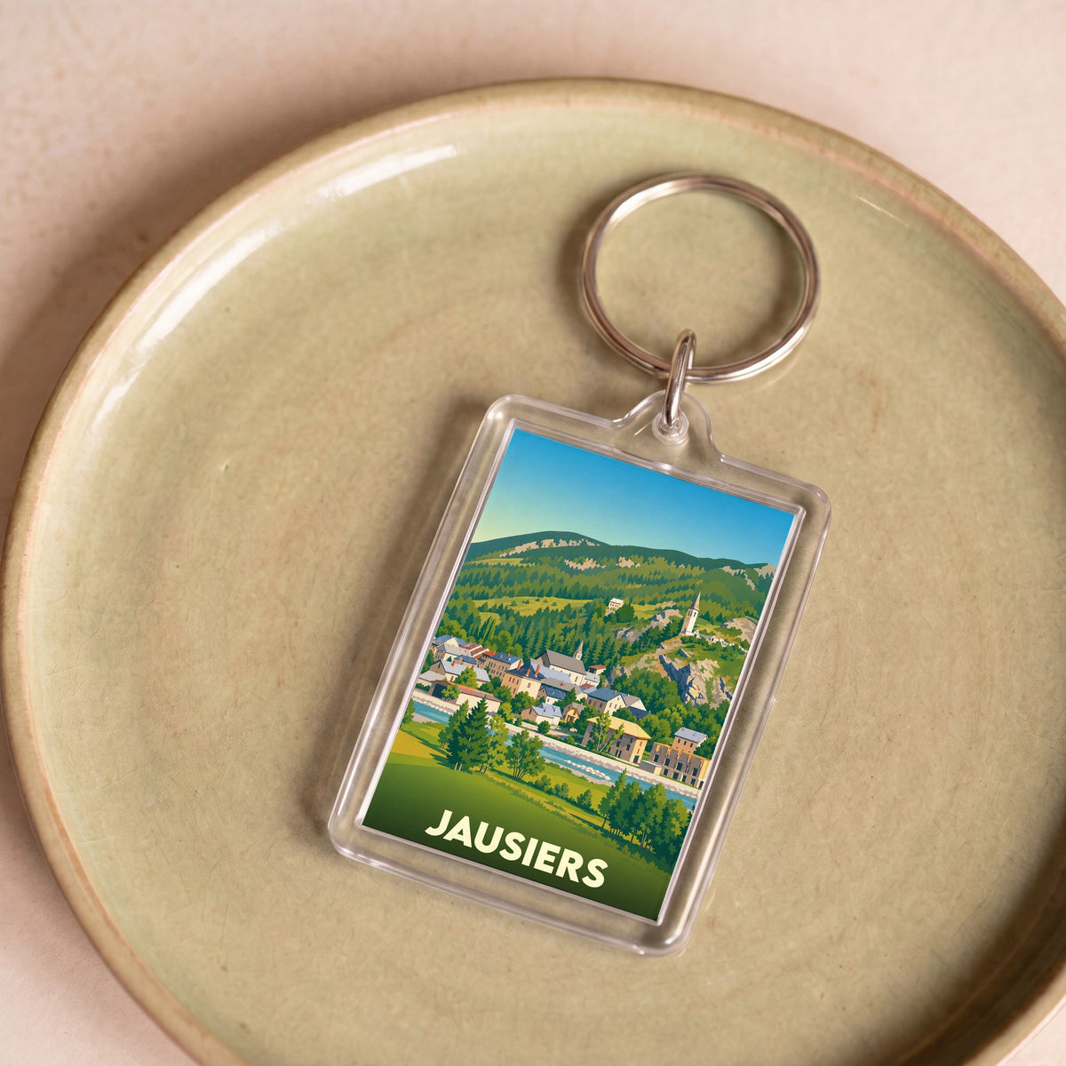 Porte-clés souvenir de la ville de Jausiers avec une illustration stylisée de son paysage montagneux.
