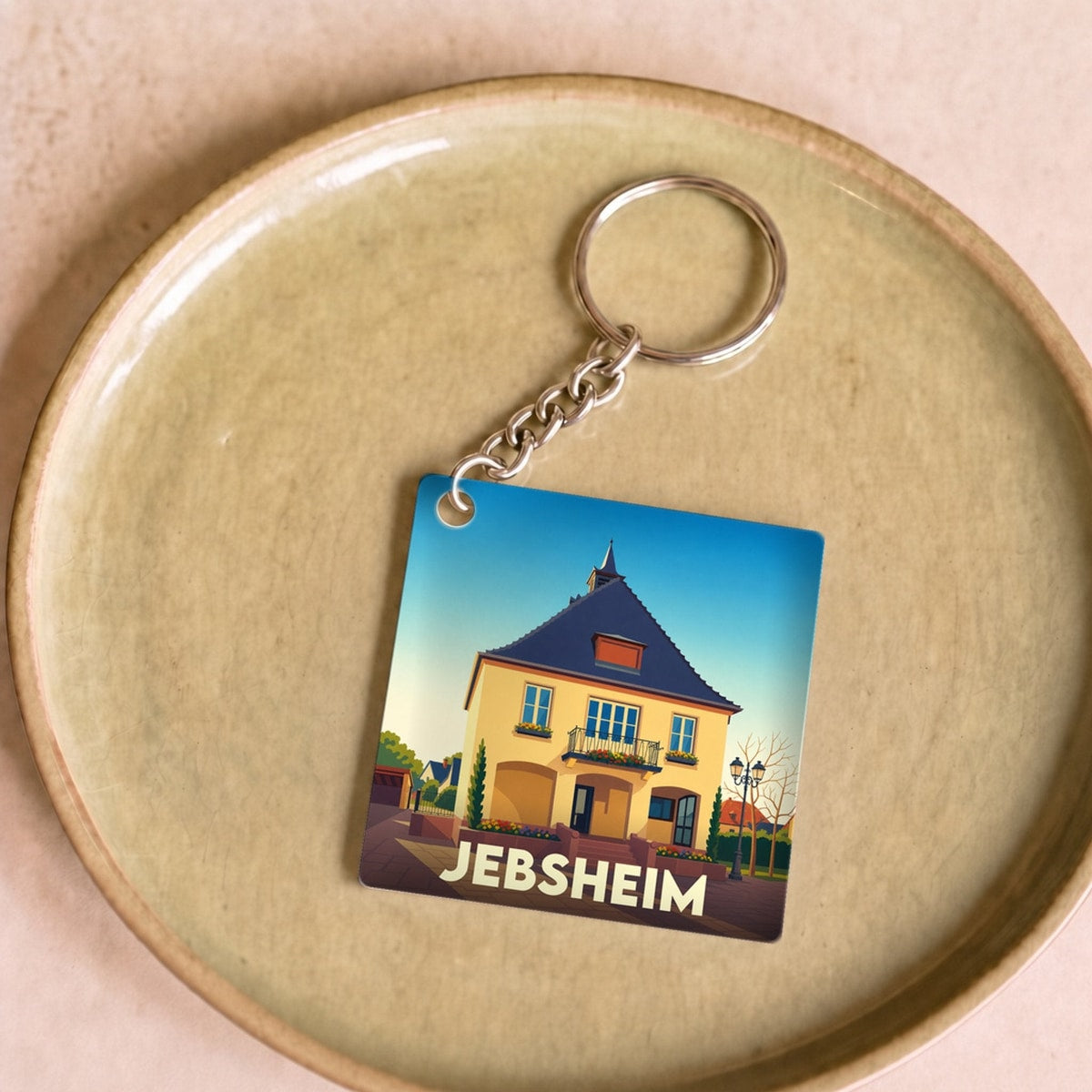 Porte-clés souvenir de la ville de Jebsheim avec une illustration stylisée.