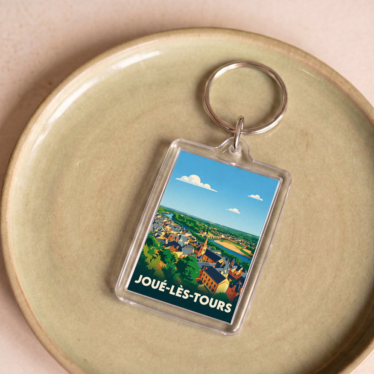 Porte-clés souvenir de la ville de Joué-lès-Tours avec une illustration stylisée du paysage urbain.