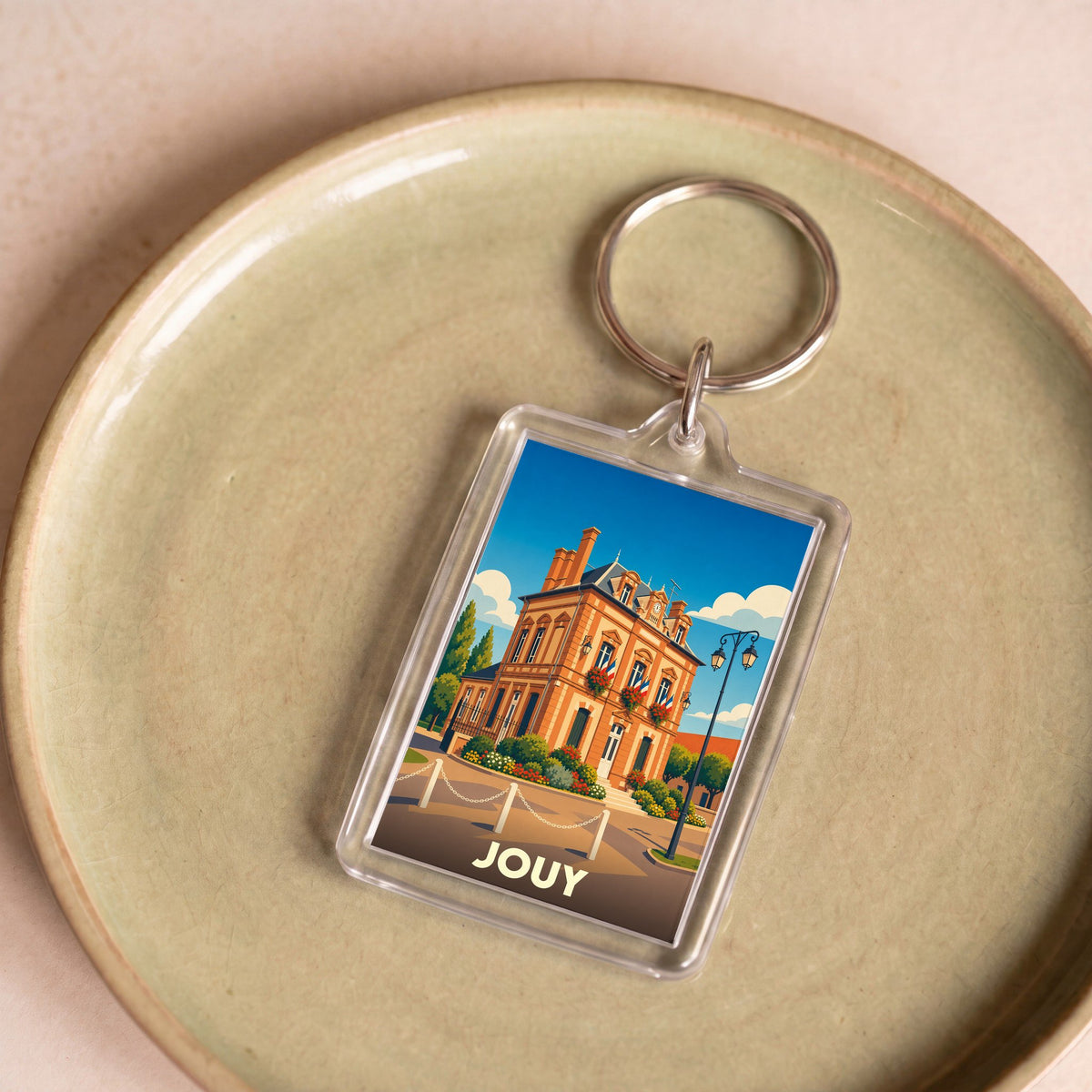Porte-clés souvenir de la ville de Jouy avec une illustration stylisée de son hôtel de ville.
