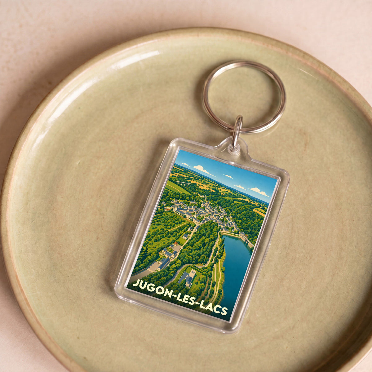 Porte-clés souvenir de la ville de Jugon-les-Lacs avec une illustration stylisée.