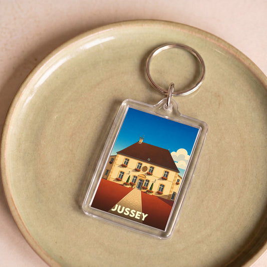 Porte-clés souvenir de la ville de Jussey avec une illustration stylisée de son hôtel de ville.