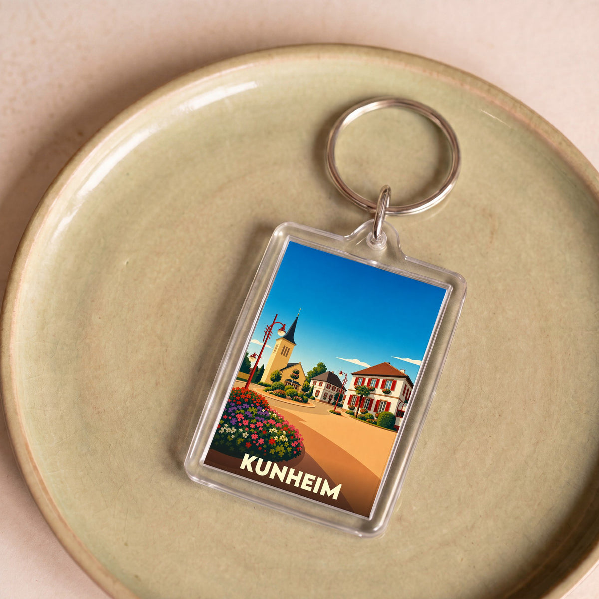 Porte-clés souvenir de la ville de Kunheim avec une illustration stylisée.