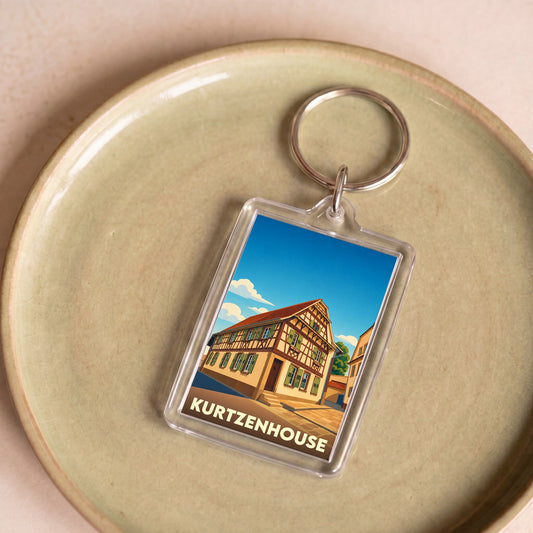Porte-clés souvenir de la ville de Kurtzenhouse avec une illustration stylisée d'une maison à colombages.