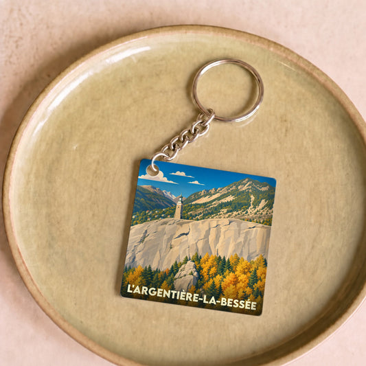 Porte-clés souvenir de la ville de L'Argentière-la-Bessée avec une illustration stylisée de ses paysages montagneux.