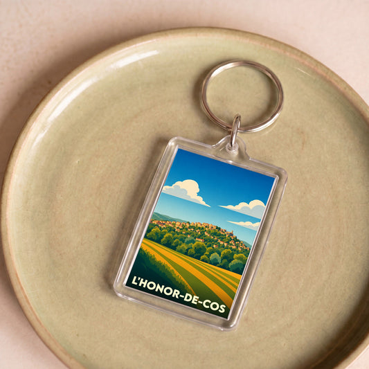 Porte-clés souvenir de la ville de L'Honor-de-Cos avec une illustration stylisée.