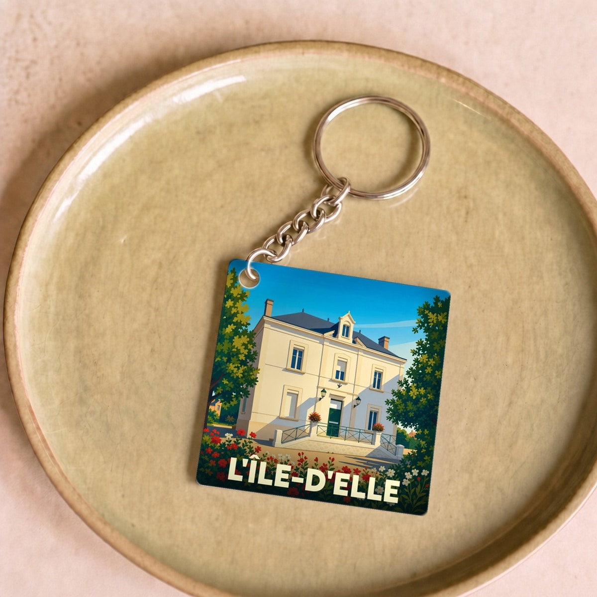 Porte-clés souvenir de la ville de L'Île-d'Elle avec une illustration stylisée d'une grande demeure.