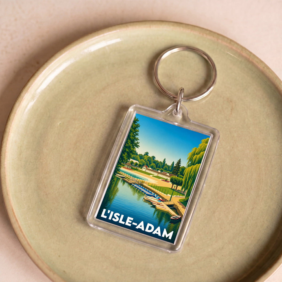 Porte-clés souvenir de la ville de L'Isle-Adam avec une illustration stylisée d'un bord de l'eau.