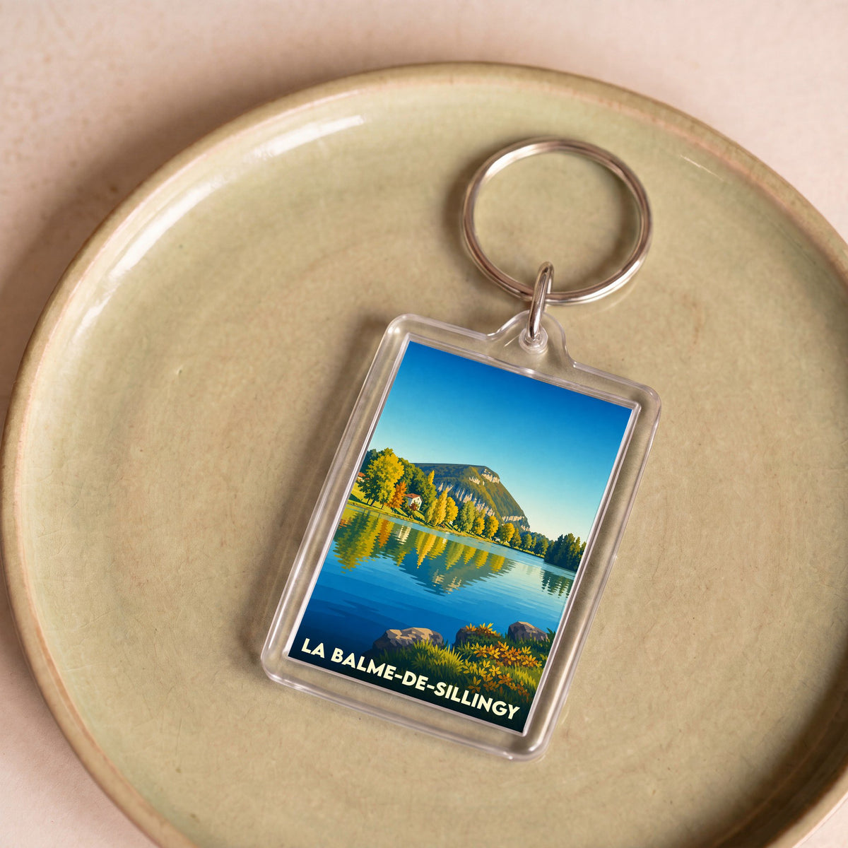 Porte-clés souvenir de la ville de La Balme-de-Sillingy avec une illustration stylisée de son lac et des montagnes.