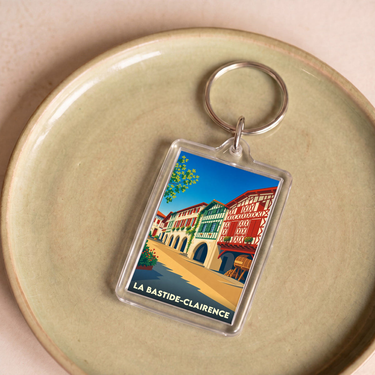 Porte-clés souvenir de la ville de La Bastide-Clairence avec une illustration stylisée de ses maisons à colombages.