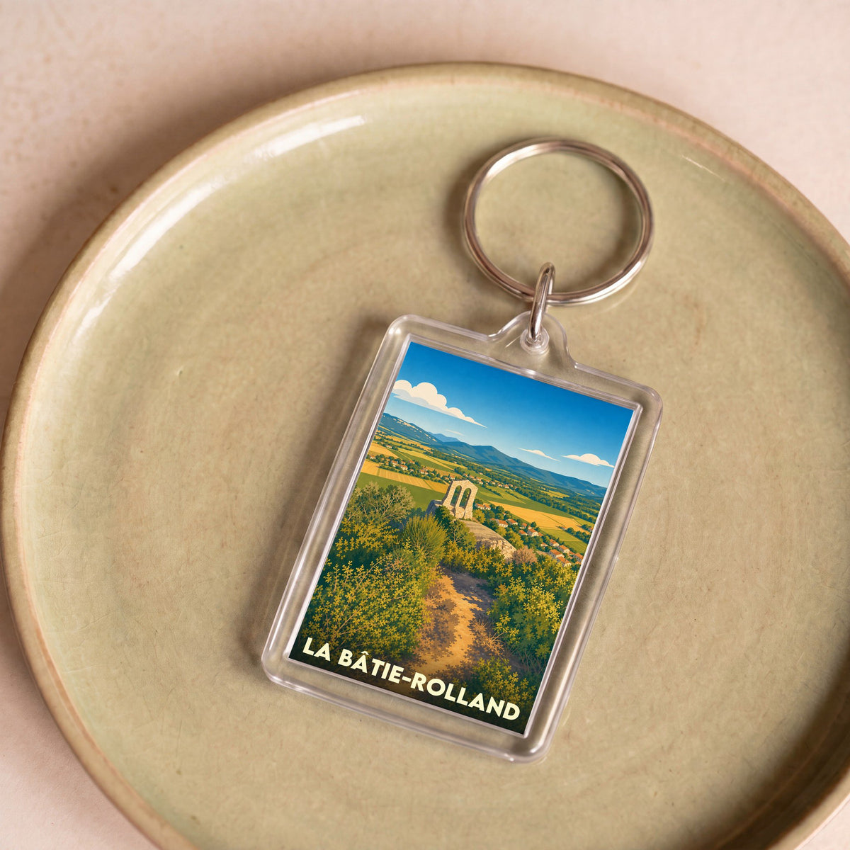 Porte-clés souvenir de la ville de La Bâtie-Rolland avec une illustration stylisée de son paysage.