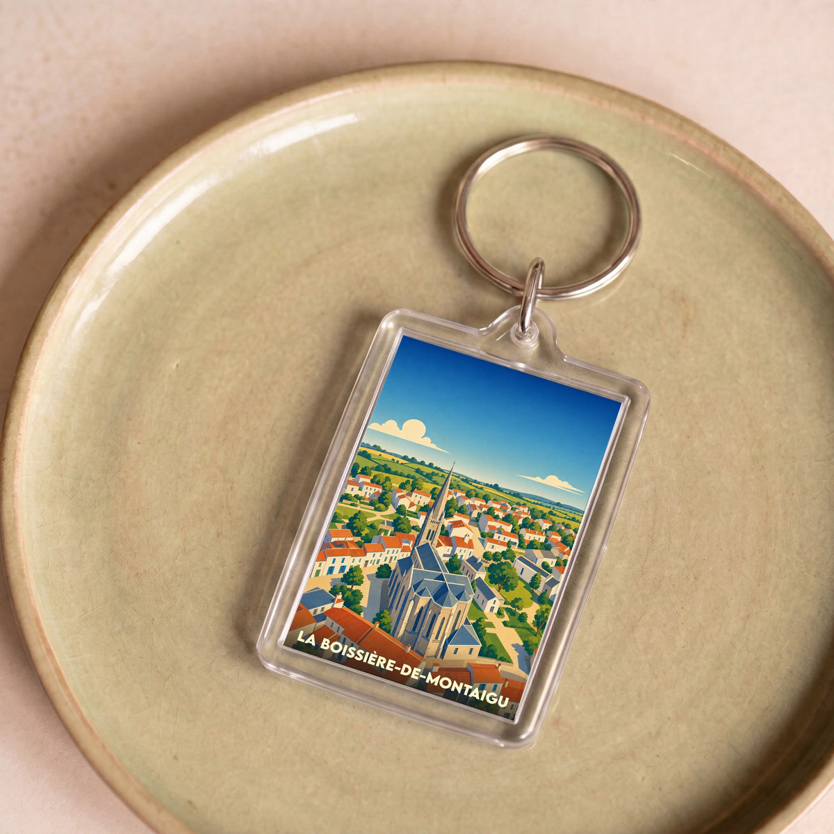 Porte-clés souvenir de la ville de La Boissière-de-Montaigu avec une illustration stylisée d'un paysage urbain.