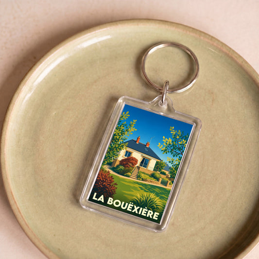 Porte-clés souvenir de la ville de La Bouëxière avec une illustration stylisée d'une maison fleurie.