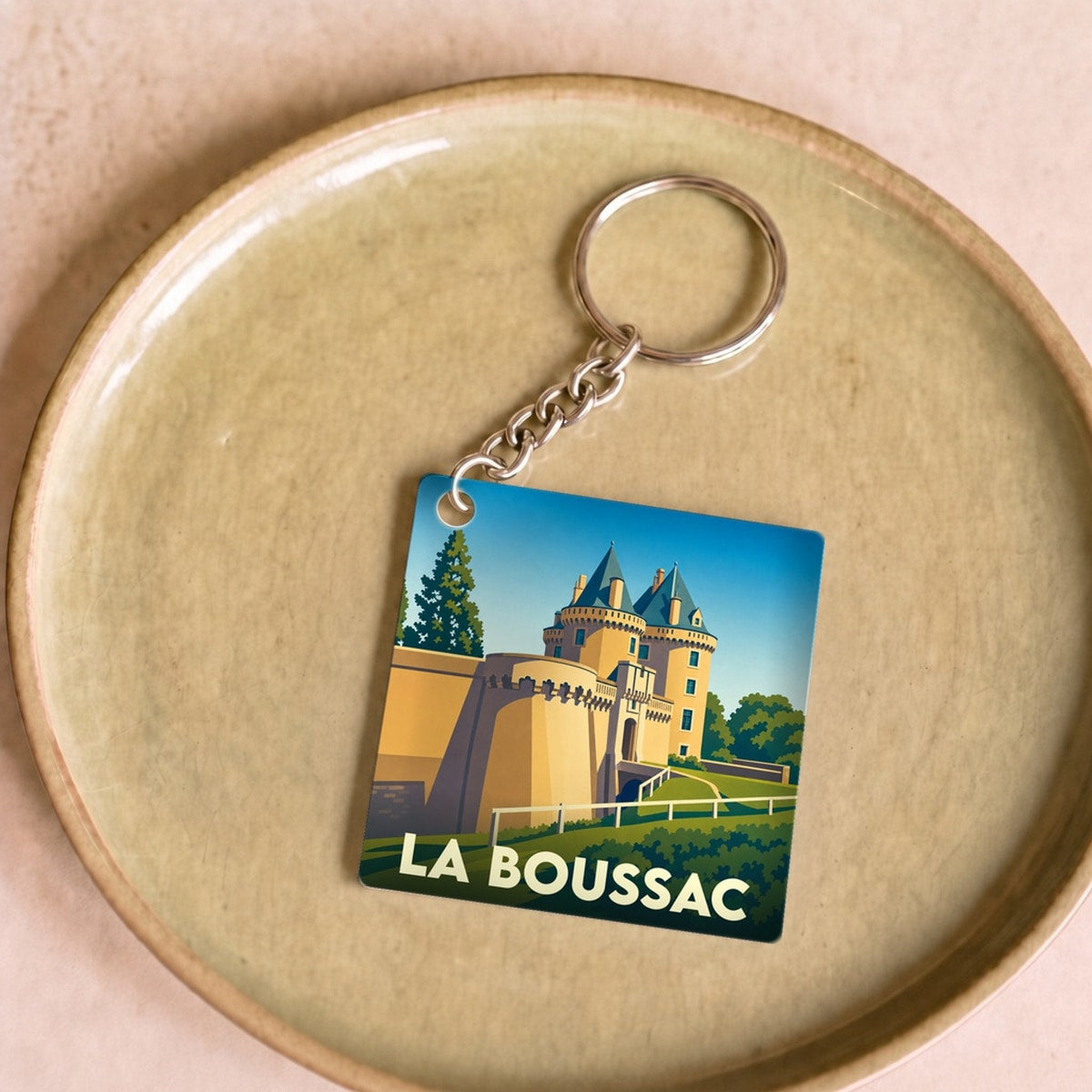 Porte-clés souvenir de la ville de La Boussac avec une illustration stylisée de son château.
