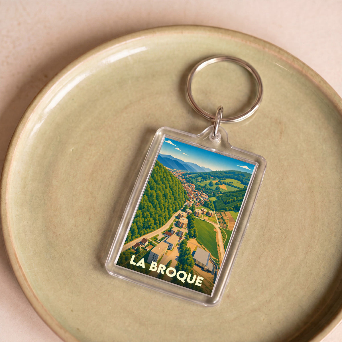 Porte-clés souvenir de la ville de La Broque avec une illustration paysagère stylisée.