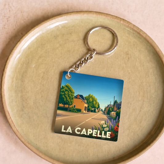 Porte-clés souvenir de la ville de La Capelle avec une illustration stylisée.