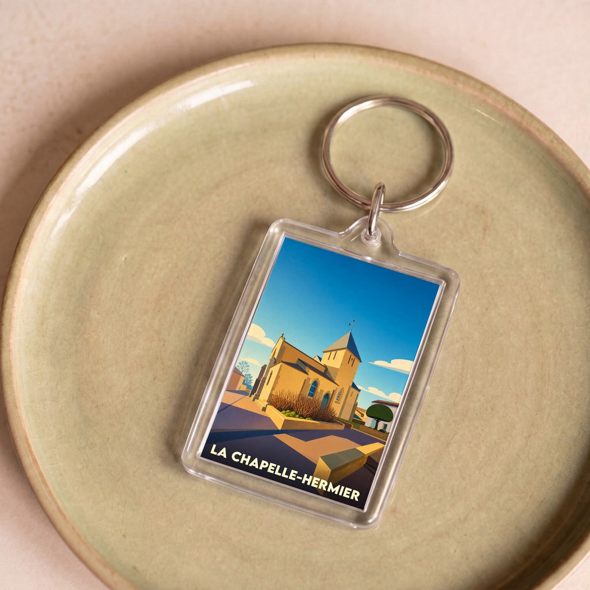 Porte-clés souvenir de la ville de La Chapelle-Hermier avec une illustration stylisée d'une église.