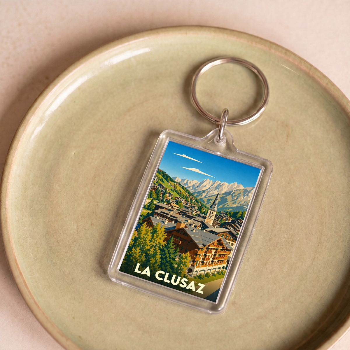 Porte-clés souvenir de la ville de La Clusaz avec une illustration stylisée de montagne.