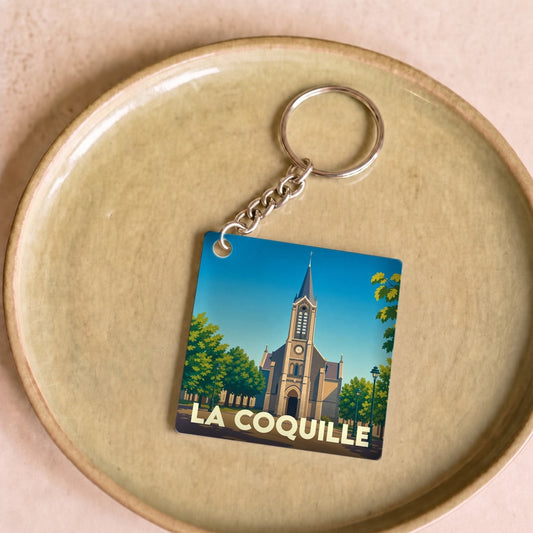 Porte-clés souvenir de la ville de La Coquille avec une illustration stylisée de son église.