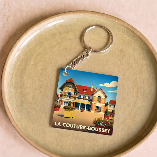 Porte-clés souvenir de la ville de La Couture-Boussey avec une illustration stylisée.