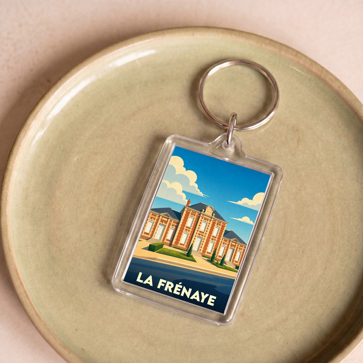 Porte-clés souvenir de la ville de La Frénaye avec une illustration stylisée de sa mairie.