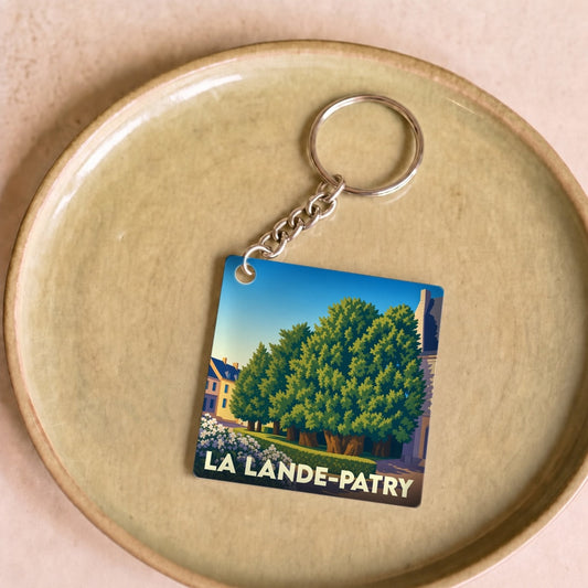 Porte-clés souvenir de la ville de La Lande-Patry avec une illustration stylisée d'un parc arboré.