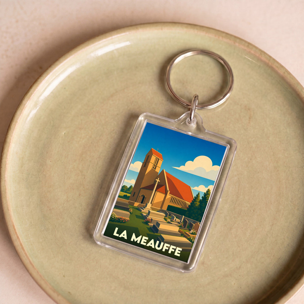 Porte-clés souvenir de la ville de La Meauffe avec une illustration stylisée de son église.