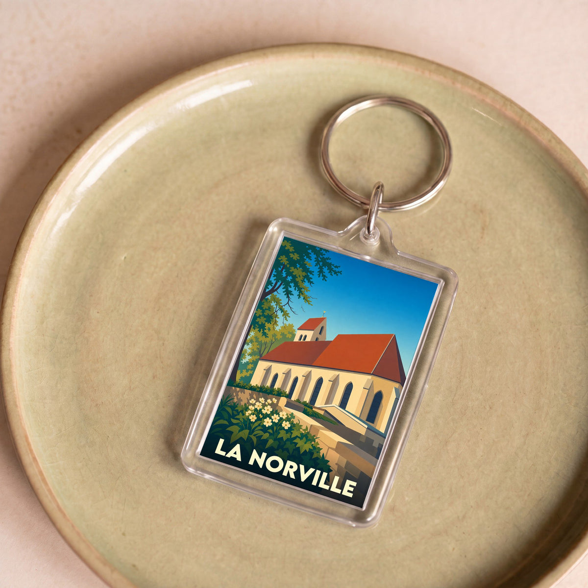 Porte-clés souvenir de la ville de La Norville avec une illustration stylisée de son église.