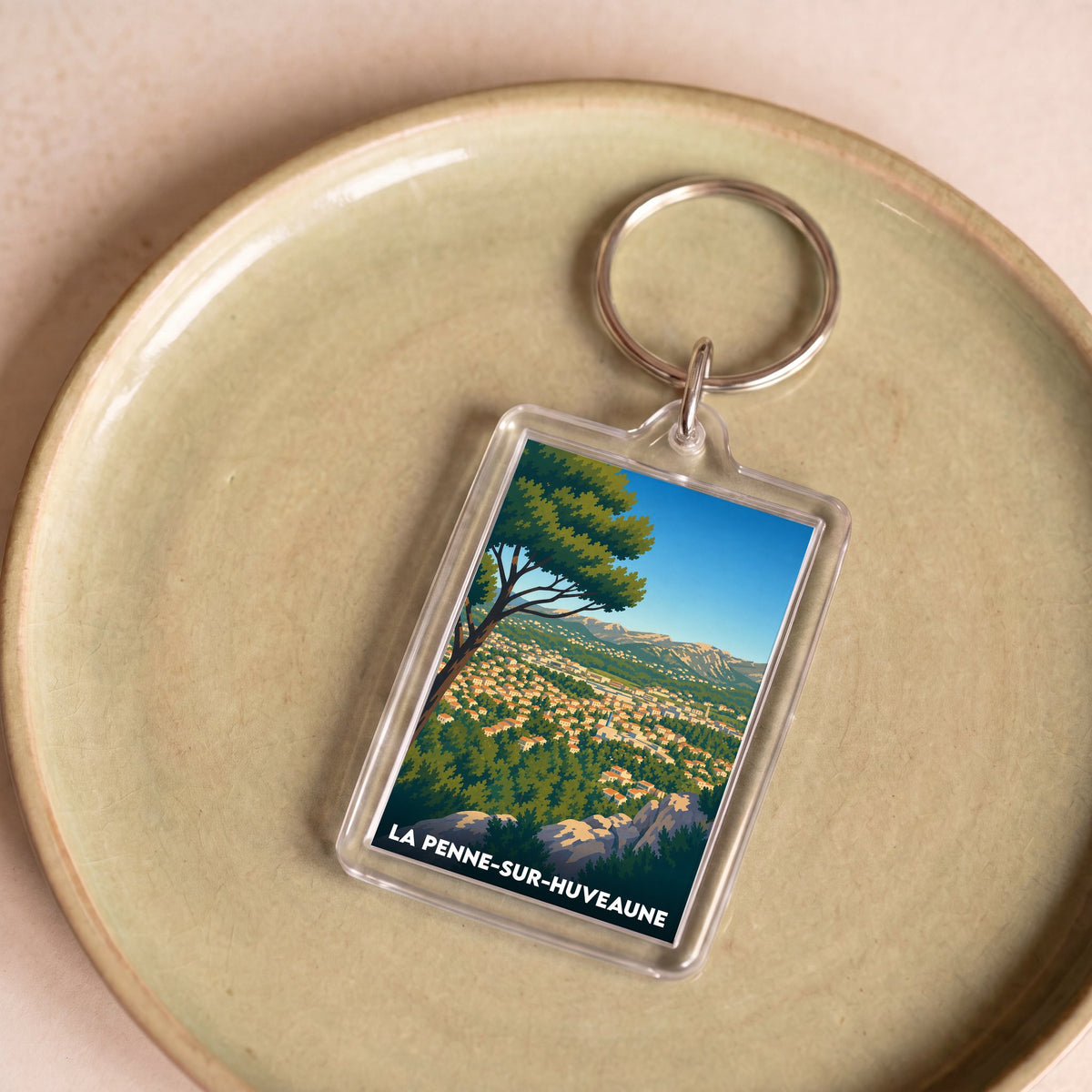 Porte-clés souvenir de la ville de La Penne-sur-Huveaune avec une illustration stylisée d'un paysage provençal.