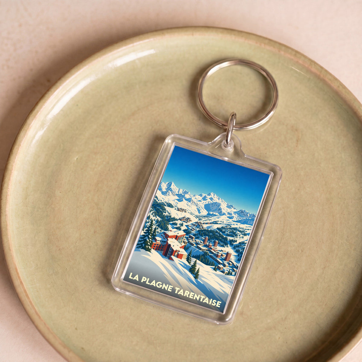 Porte-clés souvenir de La Plagne Tarentaise avec une illustration stylisée d'une station de ski enneigée.