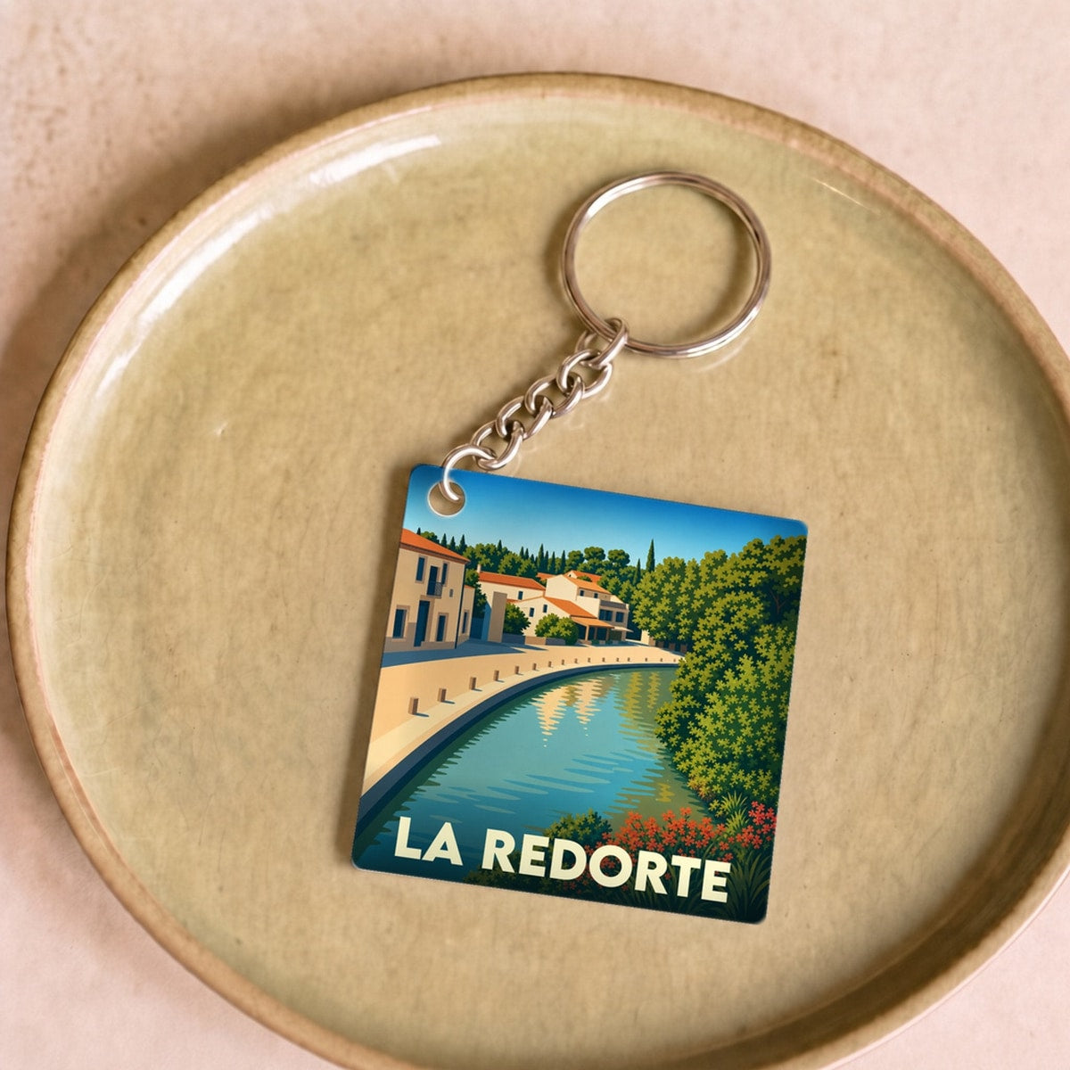 Porte-clés souvenir de la ville de La Redorte avec une illustration stylisée du canal et de ses maisons.