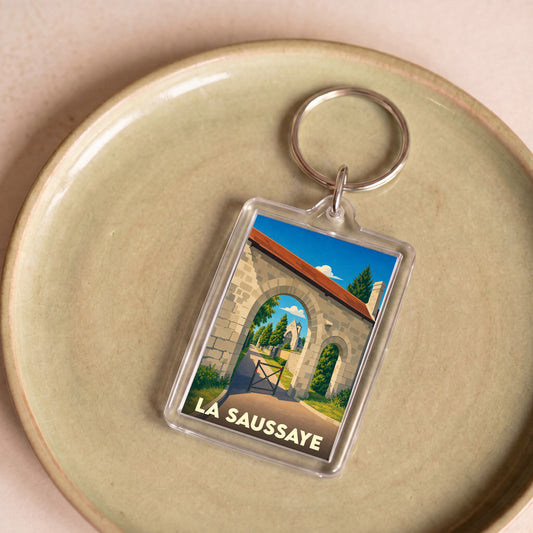 Porte-clés souvenir de la ville de La Saussaye avec une illustration stylisée d'un porche médiéval.