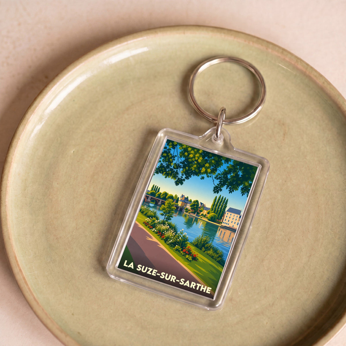 Porte-clés souvenir de la ville de La Suze-sur-Sarthe avec une illustration stylisée des bords de la Sarthe.