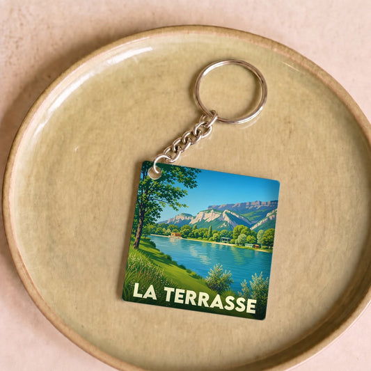 Porte-clés souvenir de la ville de La Terrasse avec une illustration stylisée de son lac et des montagnes.