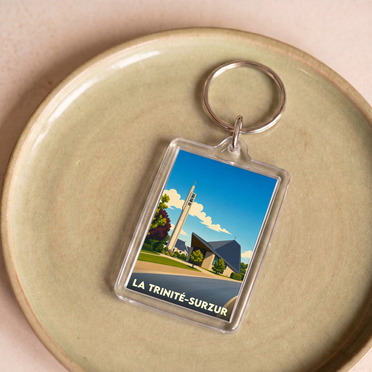 Porte-clés souvenir de la ville de La Trinité-Surzur avec une illustration stylisée de son église moderne.