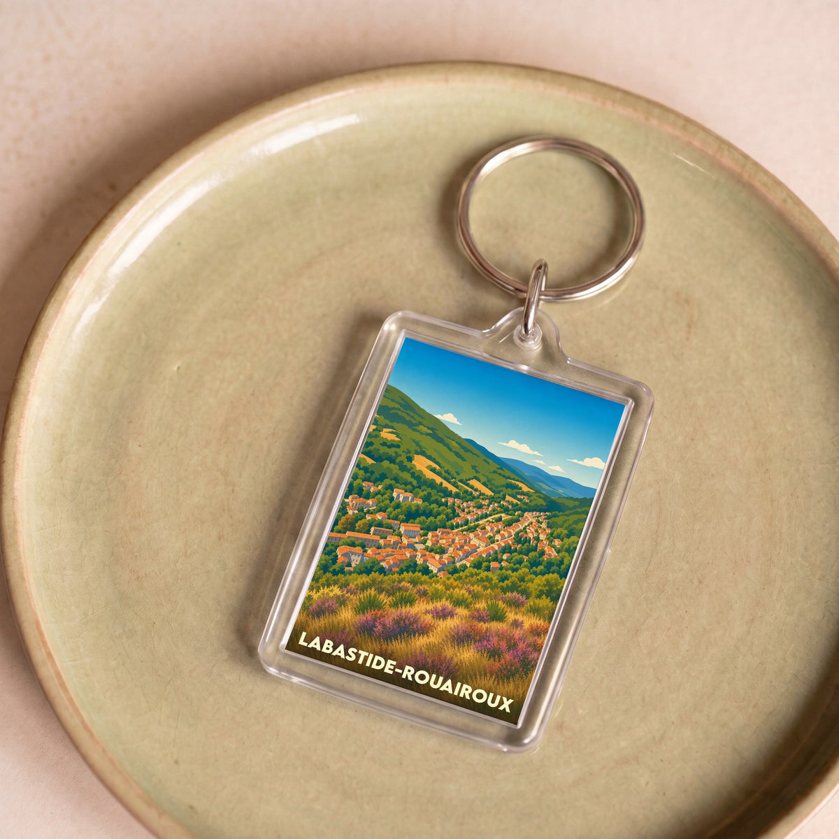 Porte-clés souvenir de la ville de Labastide-Rouairoux avec une illustration paysagère stylisée.